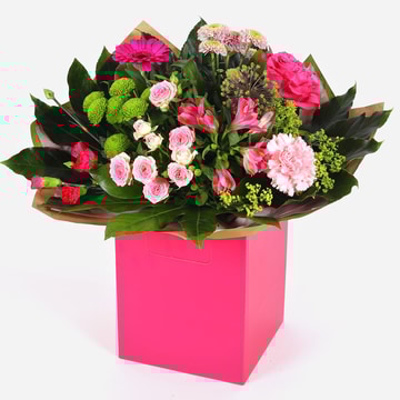 Blushing meadow bouquet with pink and green seasonal flowers in bright pink gift box