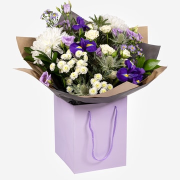 Violet hand tied bouquet with purple and white flowers in a gift bag