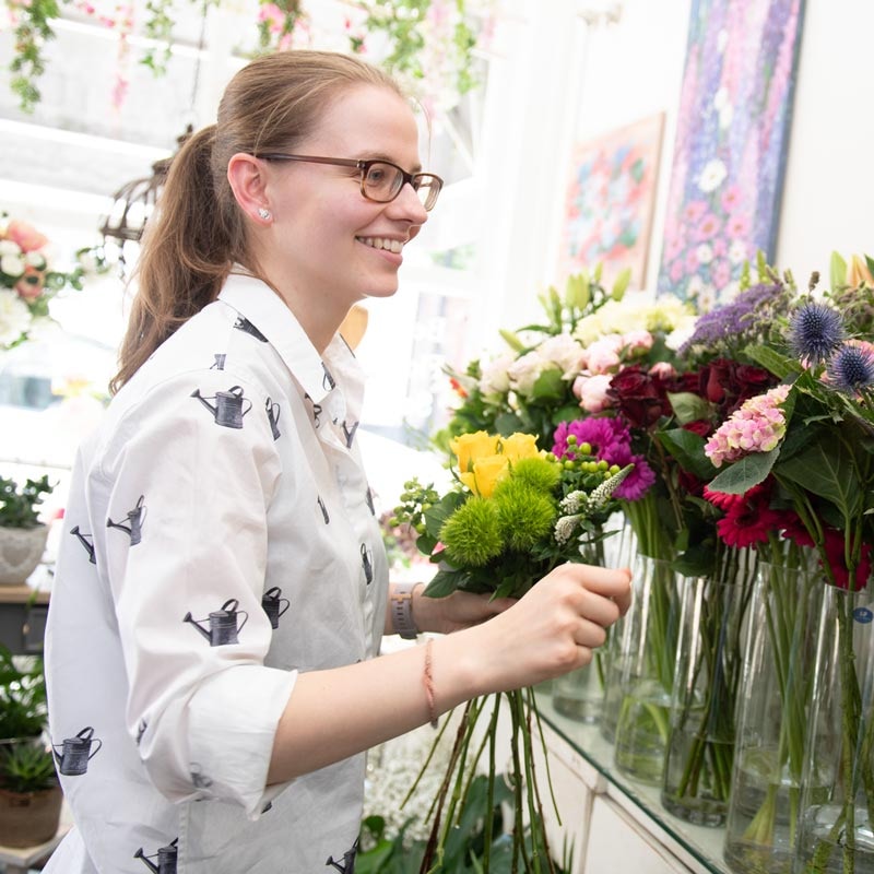 Smiling florist arranging fresh flowers in a shop