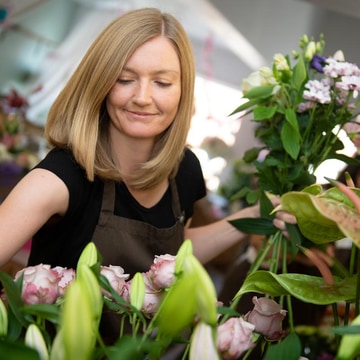 Florist choice gift wrap smiling florist arranging flowers in a shop