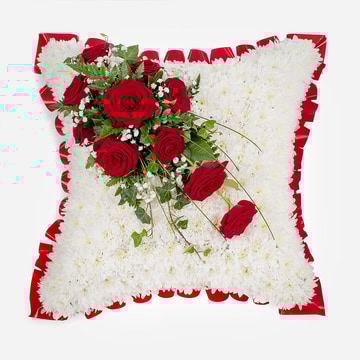 White funeral cushion tribute with red roses and red ribbon edging