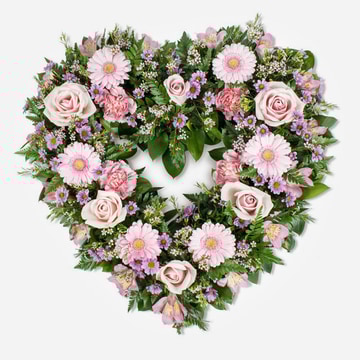 Heart shaped funeral tribute in soft pink tones with roses gerberas and carnations