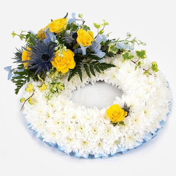 White massed funeral wreath with yellow roses and blue flowers