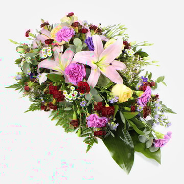 Multi coloured funeral spray with lilies carnations and roses arranged in an oasis tray