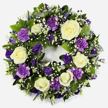 Funeral wreath with white roses purple carnations and lisianthus on a 12 inch base