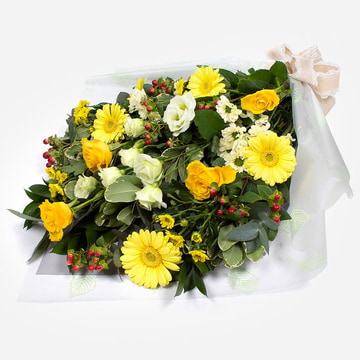 Yellow and white funeral bouquet in cellophane with roses gerbera and foliage