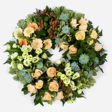 Eco funeral wreath with peach roses gerbera green lisianthus and red hypericum on a foliage base