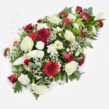 Red and white single ended funeral spray featuring roses lilies and carnations