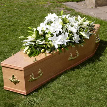 Graceful casket spray of white lilies and greenery