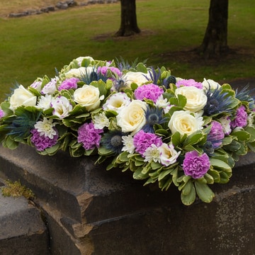 Pillow shaped tribute with lilac and white flowers