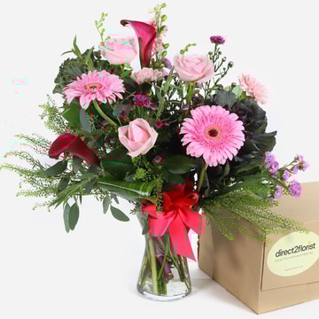 French riviera pink roses gerberas and calla lilies in a vase with a red ribbon
