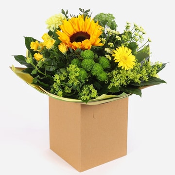 Yellow sunflower bouquet with seasonal blooms and greenery in a kraft gift box