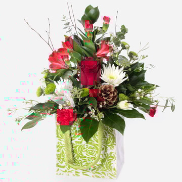 Festive christmas arrangement presented in a patterned gift bag