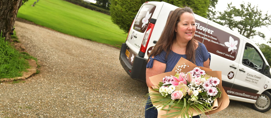 Friendly florist holding a vibrant bouquet from a flower delivery van for local flower delivery