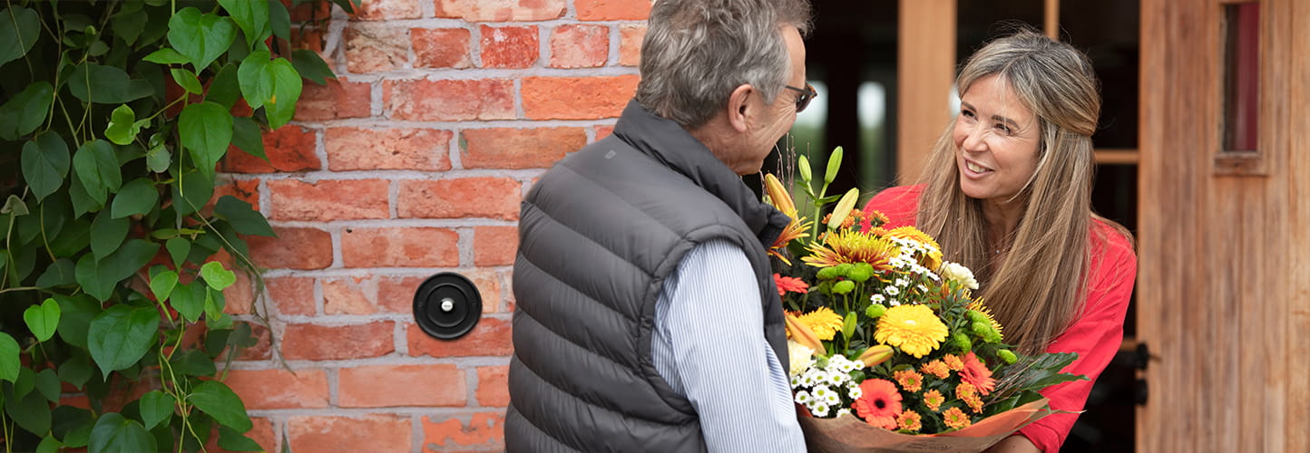 Woman delivering a vibrant bouquet to a customer at the front door