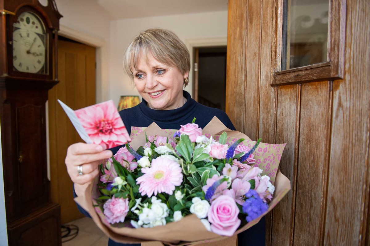 Grandmother receiving bouquet of flowers and reading card message