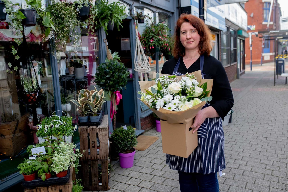 Local Irish florist with white flower bouquet outside her shop