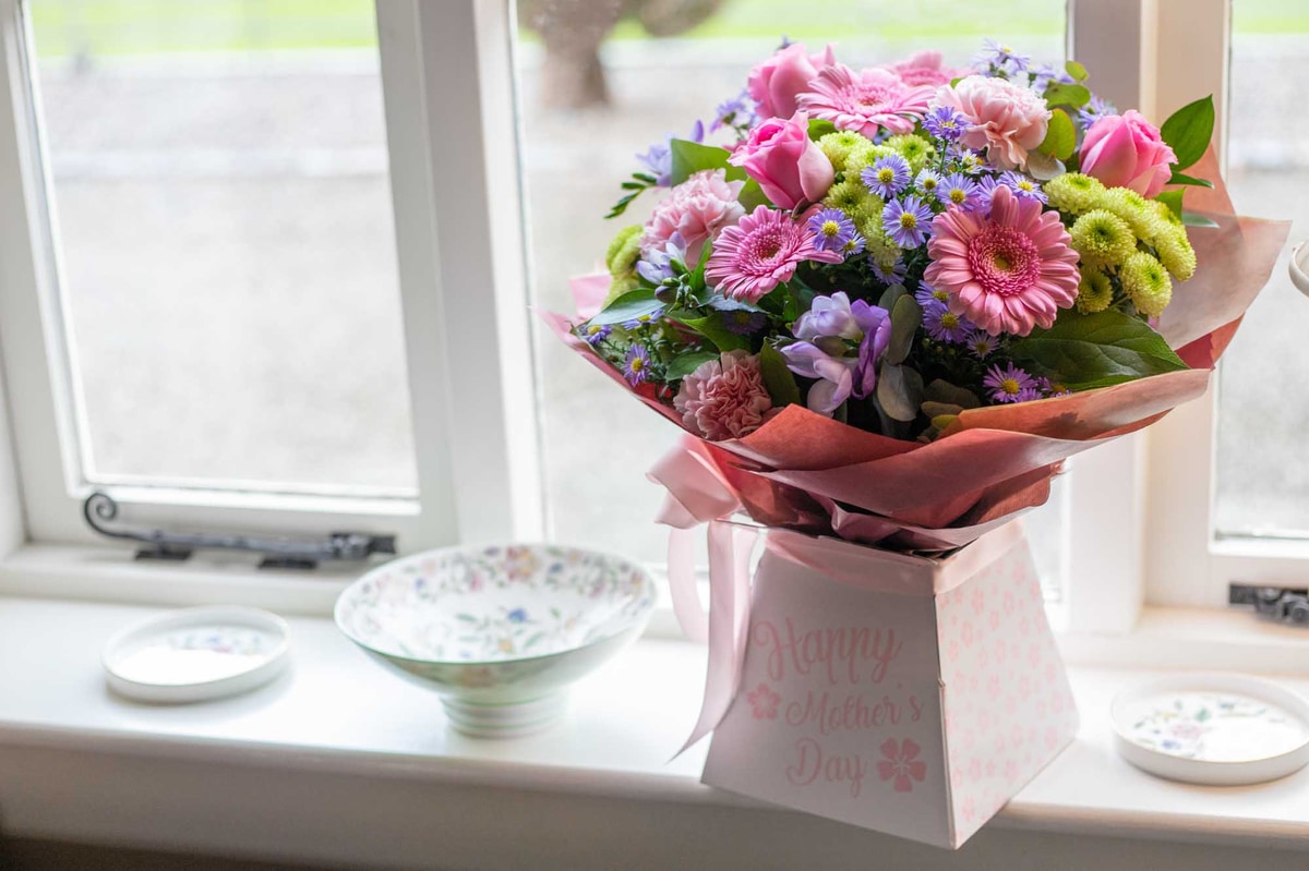Pink flower bouquet for Mother's Day delivery in Ireland on windowsill with Happy Mother's Day message on box