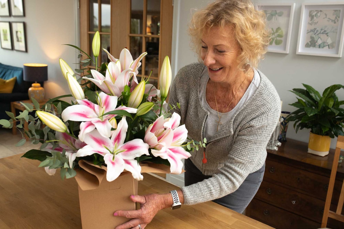 Woman arranging expensive flower bouquet on side table